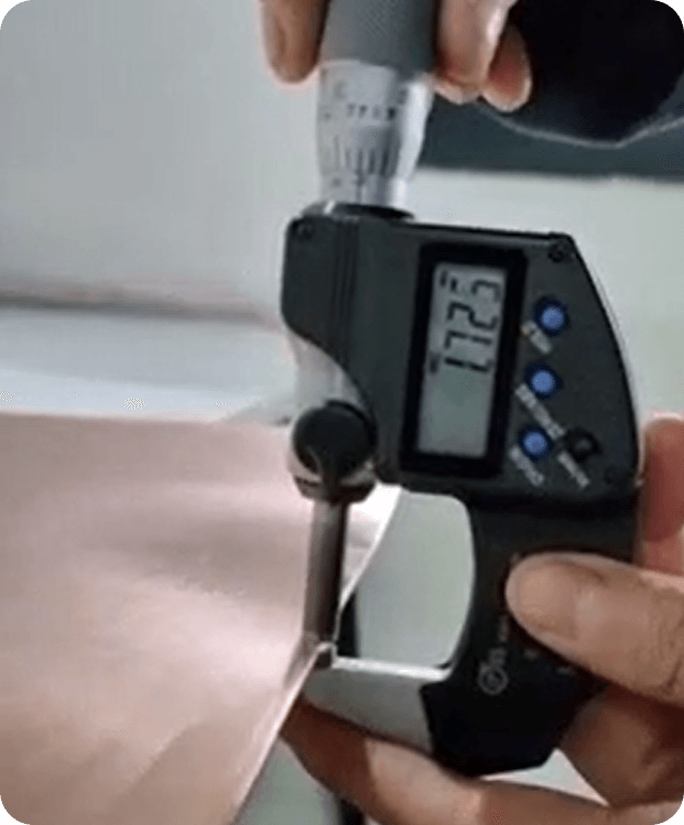 A technician measuring the thickness of a copper foil roll